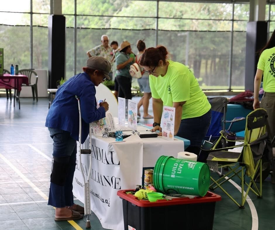 HAKA volunteer assisting a community member at a HAKA information table